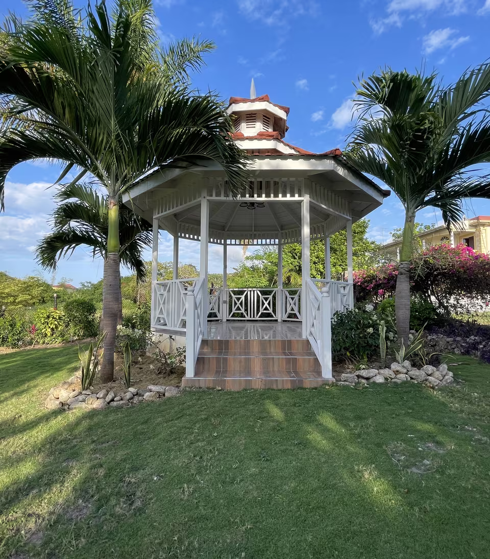 The white gazebo on the lawn, framed by palms