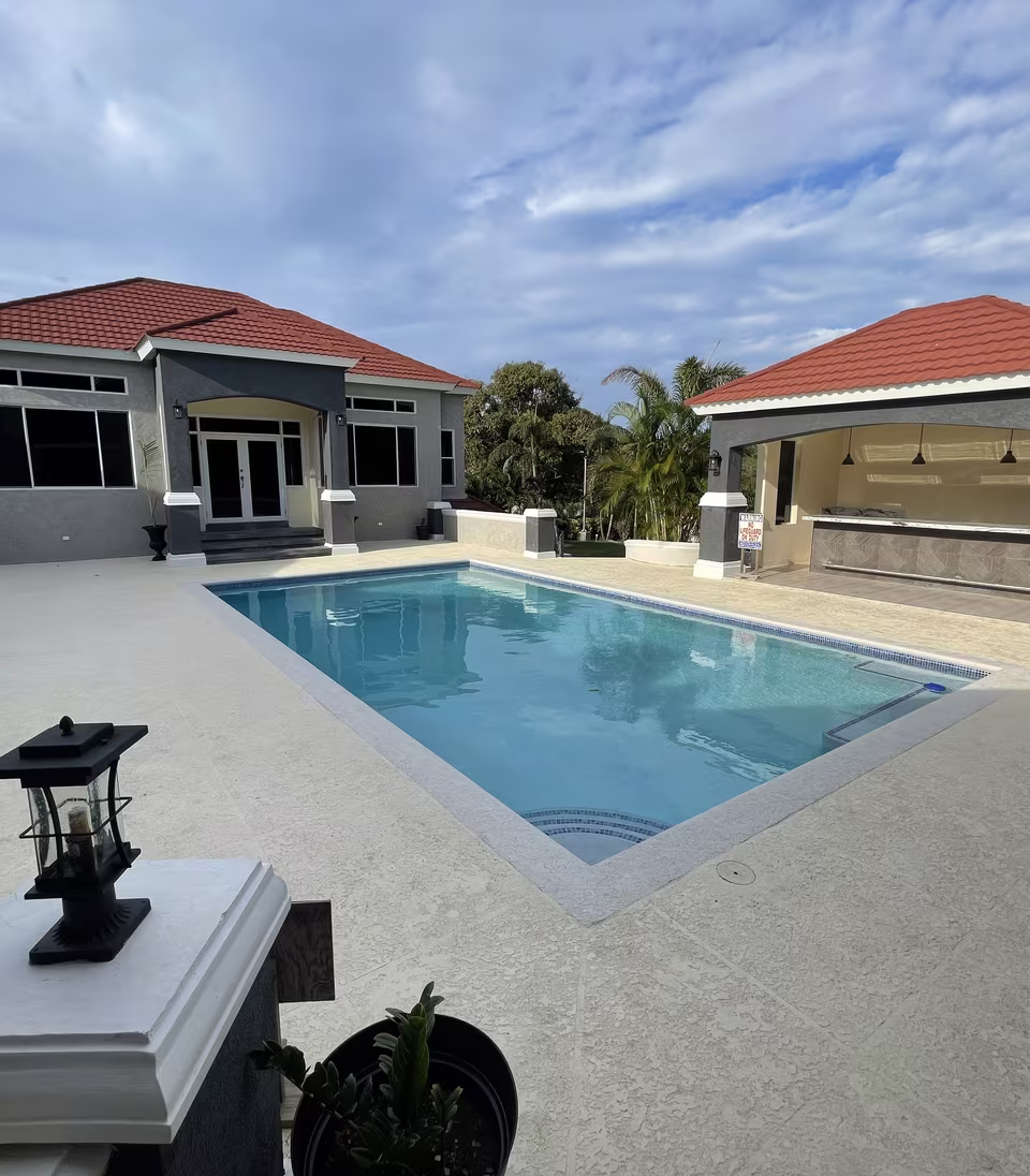 The pool deck looking across the water to the house and covered bar